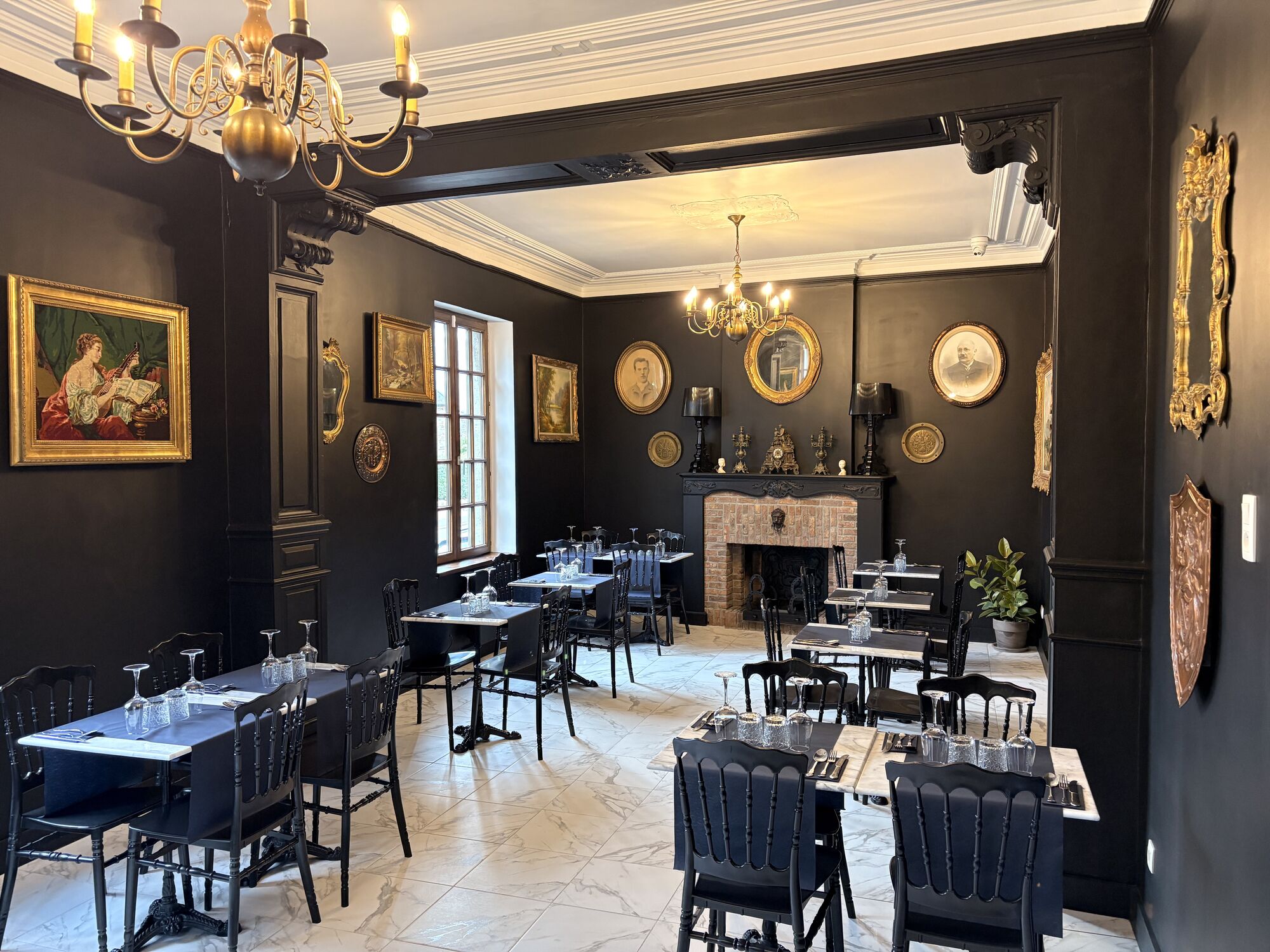 Salle de La Toque Noire Ristorante avec sa cheminée, ses lustres dorés et ses portraits anciens